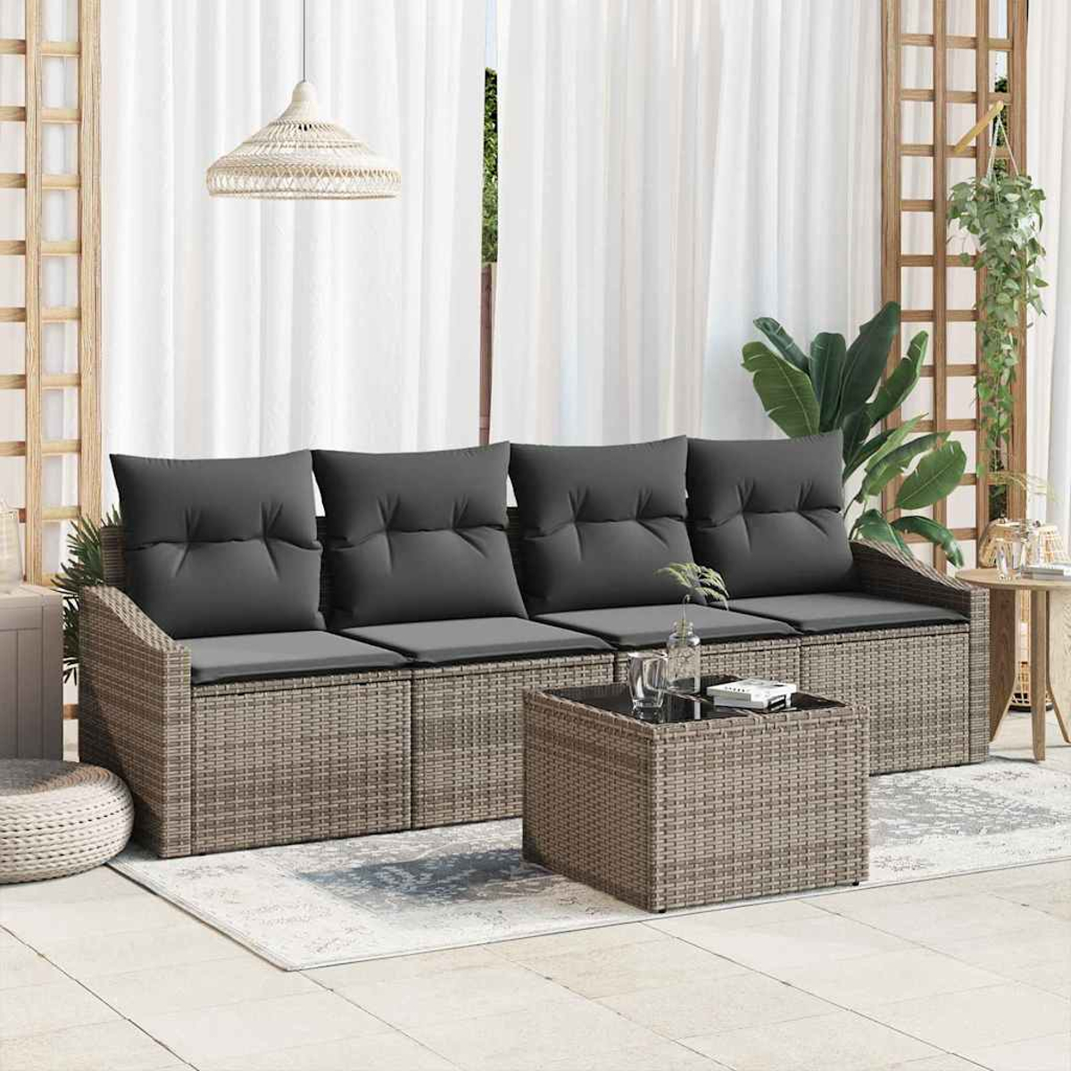 Ein Korbmöbel-Sofa mit grauen Kissen und einem passenden Couchtisch. Weiße Vorhänge und Pflanzen im Hintergrund schaffen eine entspannte Szene.