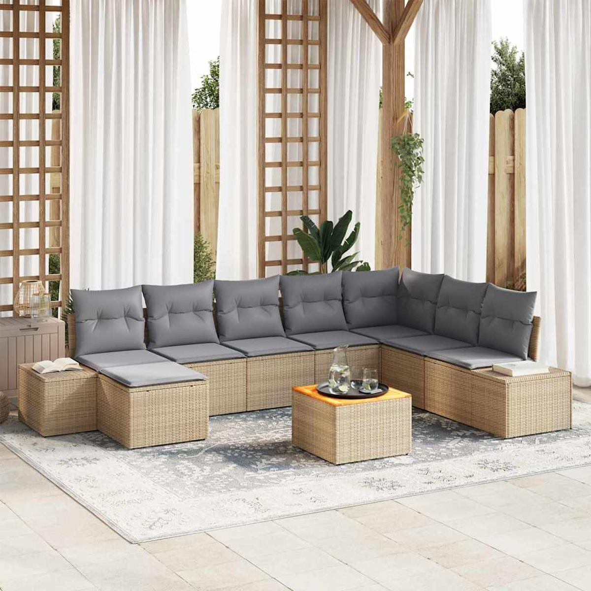 Außenbereich mit grauen Kissen, Rattangehäuse und einem Couchtisch. Weiße Vorhänge und Holzstrukturen im Hintergrund.