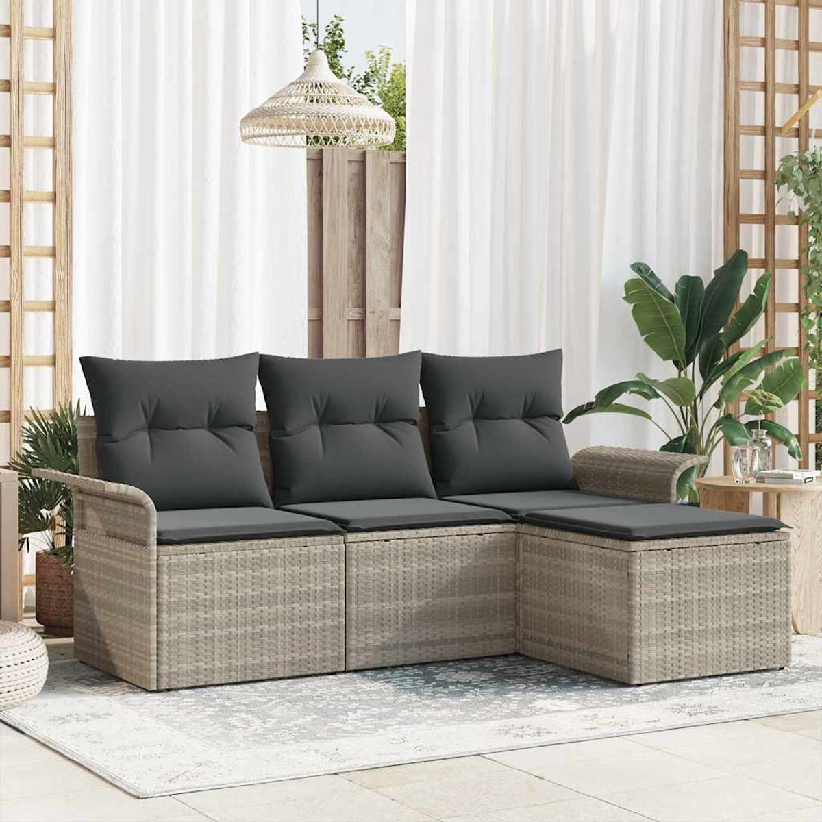 Geflochtenes Outdoor-Sofa mit grauen Kissen. Weiße Vorhänge und Pflanzen im Hintergrund. Eine gewebte Lampe hängt darüber.