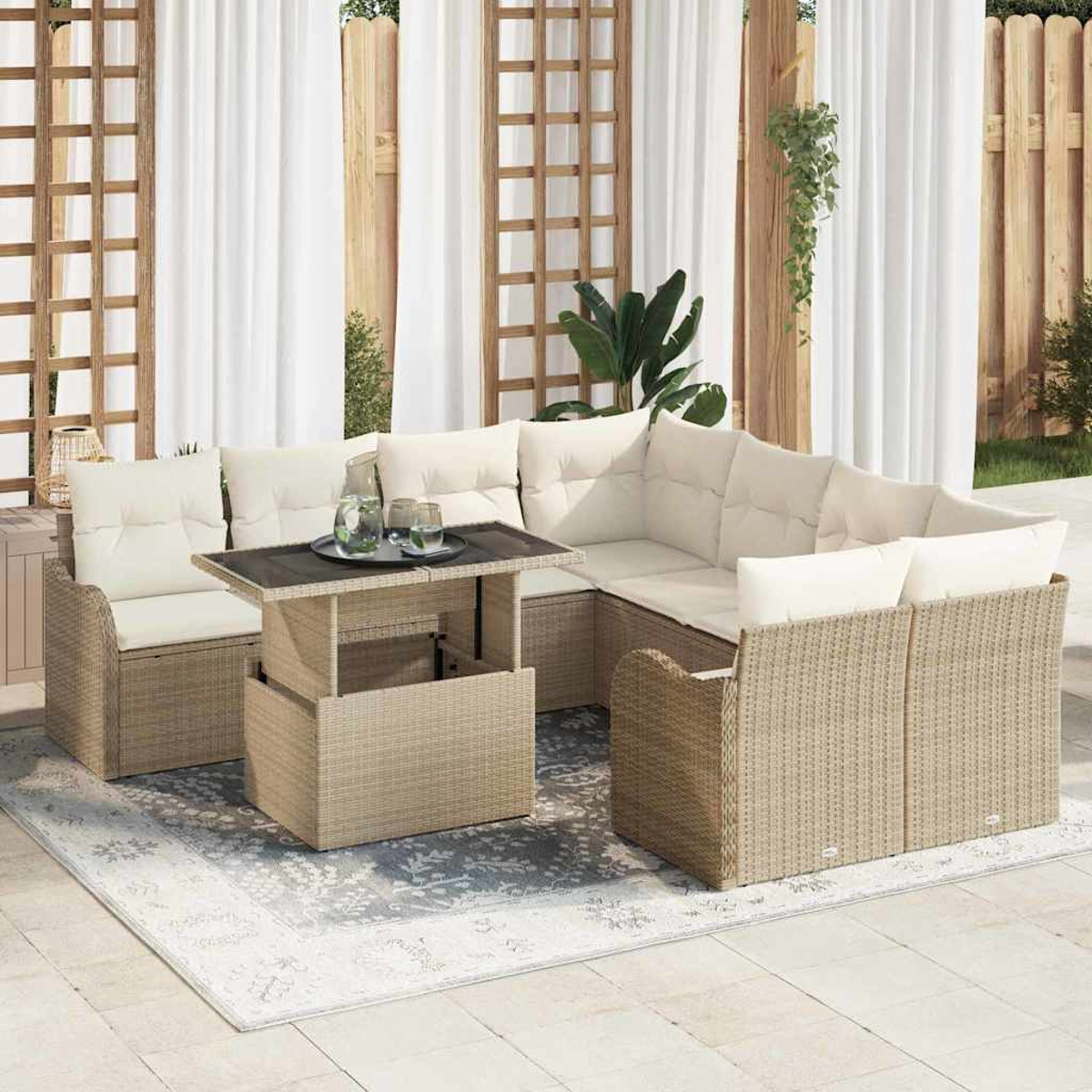 Outdoor-Sitzbereich mit hellbeigen Korbmöbeln, weißen Kissen und einem Tisch mit Hubfunktion auf einem gemusterten Teppich.