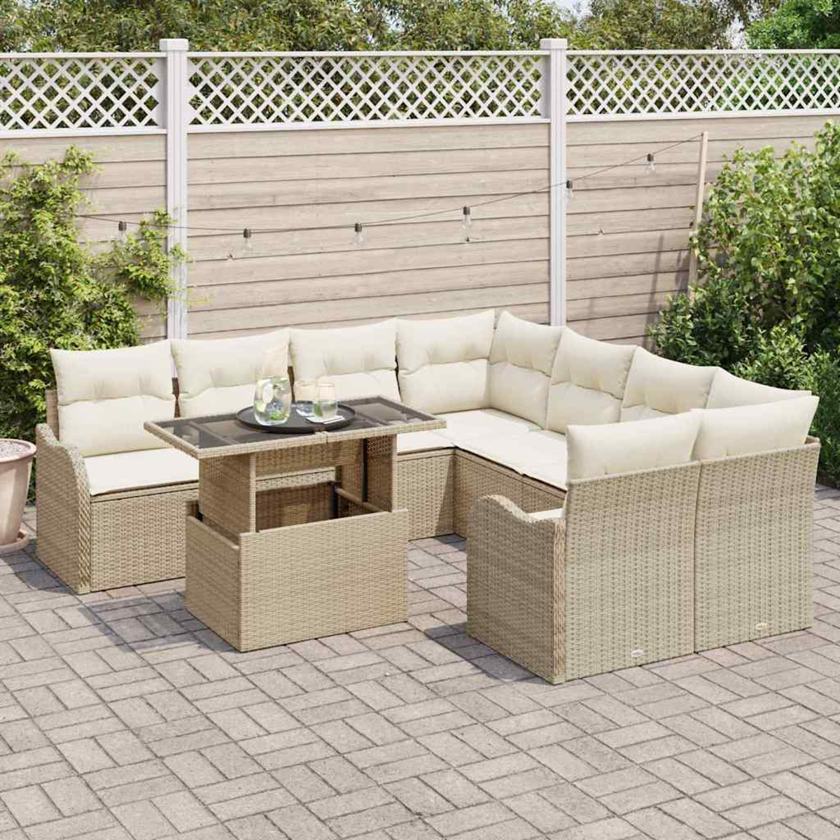 Beige Outdoor-Geflechtsitzgruppe mit cremefarbenen Kissen, Glastisch und Holzzaun im Hintergrund, Terrassenfliesen.