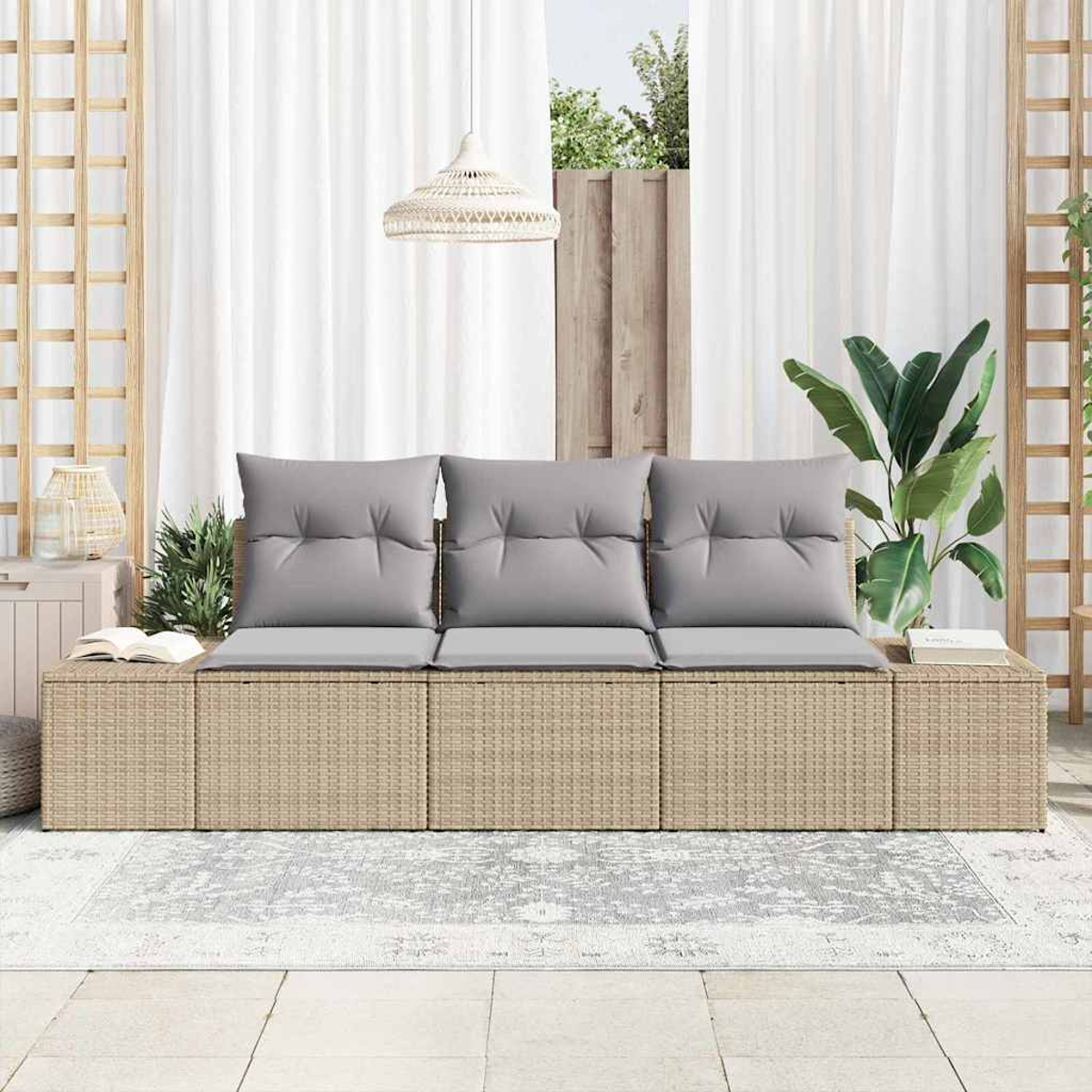 Ein beiges geflochtenes Sofa mit grauen Kissen steht auf einem gemusterten Teppich. Weiße Vorhänge und eine Hängelampe sind im Hintergrund.