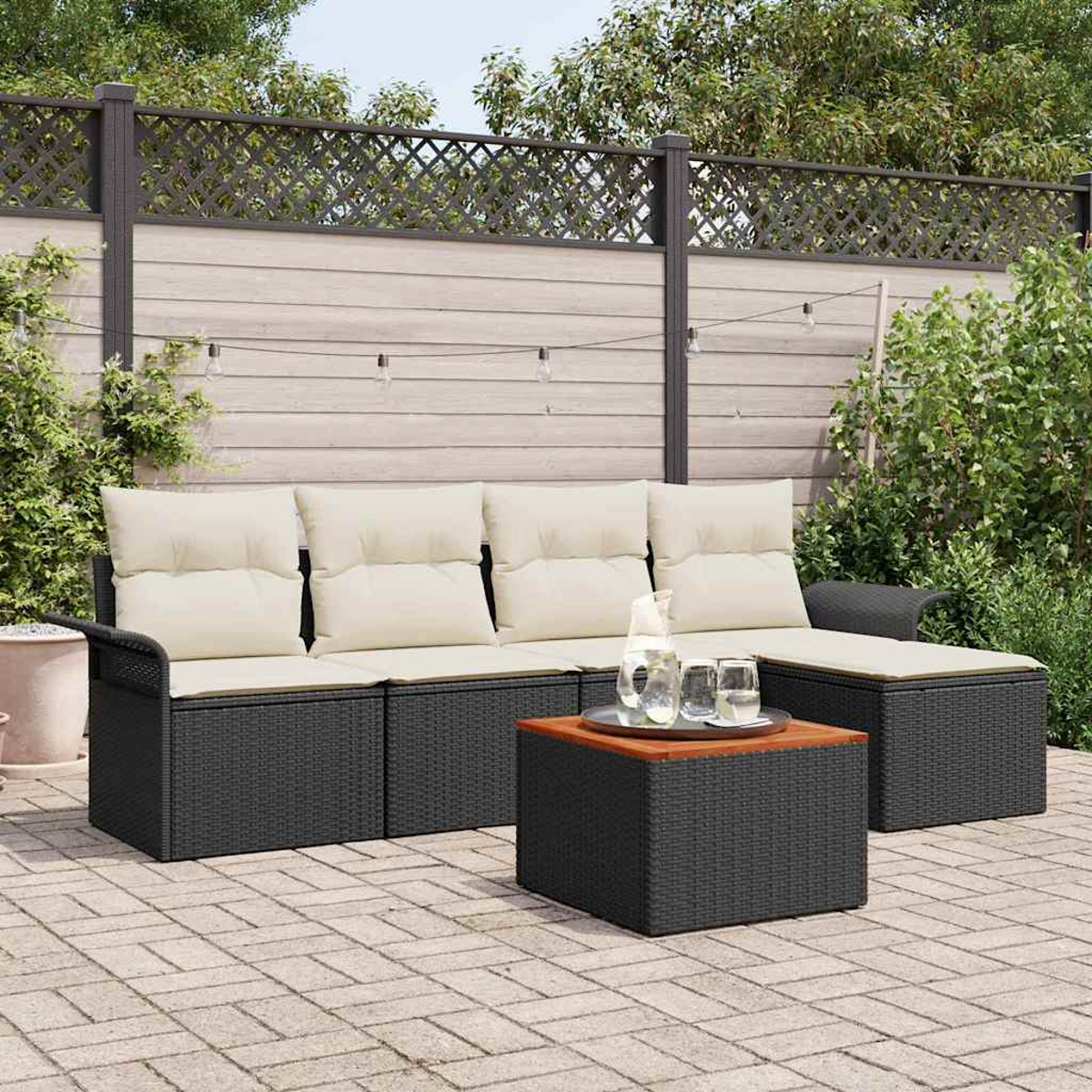 Szene im Freien mit schwarzem Korbmöbel-Sofa und Couchtisch. Beige Kissen. Wasserkrug und Gläser auf dem Tisch. Holzzaun im Hintergrund.
