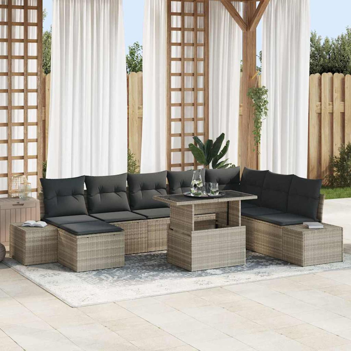 Gartenmöbel-Set. Graue Kissen auf Korbsitzen. Tisch mit Gläsern. Weiße Vorhänge. Holzpergola.