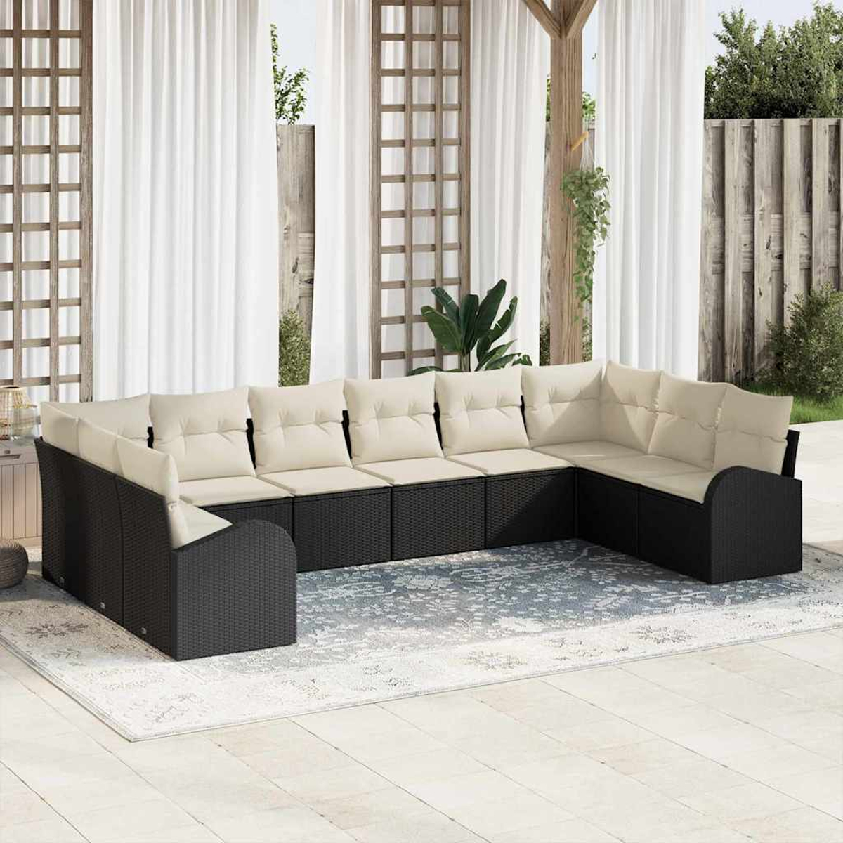 Ein Outdoor-Ecksofa mit cremefarbenen Kissen steht auf einem Teppich. Weiße Vorhänge und ein Holzgitter umrahmen die Aussicht.