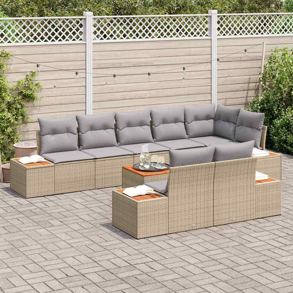 Garten-Sitzgruppe mit grauen Kissen. Sie hat ein beiges, gewebtes Gestell, kleine Tische und im Hintergrund einen Holzzaun und Pflanzen.