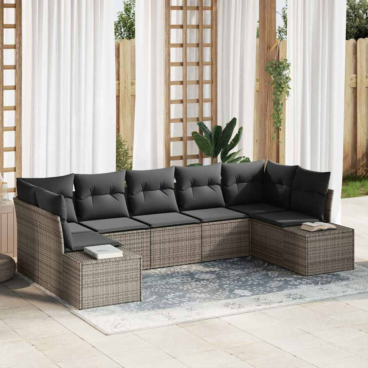 Outdoor-Ecksofa mit grauen Kissen auf einem Teppich. Weiße Vorhänge und Holzgitter im Hintergrund. Pflanzen sichtbar.