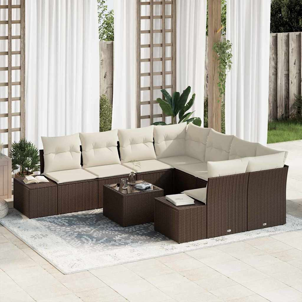 Sofá seccional exterior con cojines crema, en un patio con alfombra y cortinas. Hay plantas y mesitas.