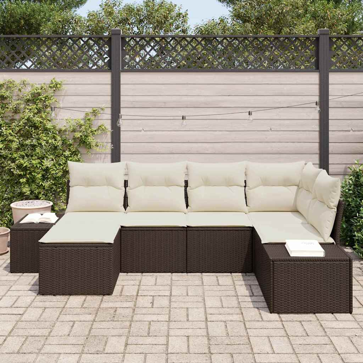 Outdoor-Ecksofa mit cremefarbenen Kissen auf brauner Korbbasis. Auf einer Terrasse mit Holzzaun als Hintergrund.