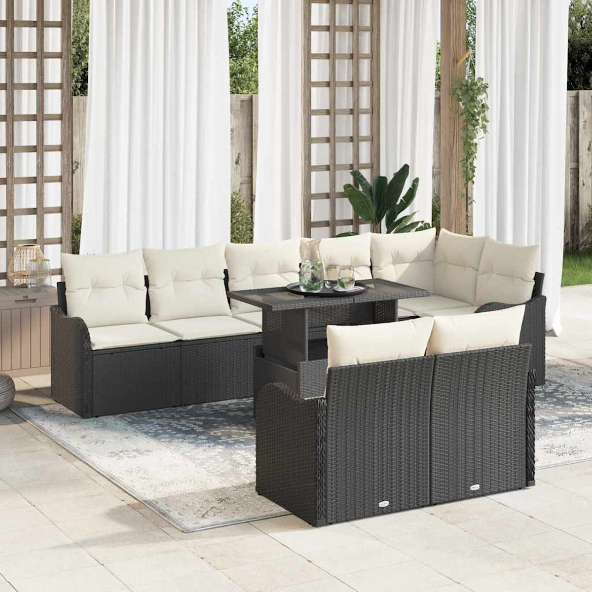 Gartenmöbel-Set mit schwarzen Korbsesseln, cremefarbenen Kissen und einem Tisch. Weiße Vorhänge im Hintergrund. Eine entspannte, helle Umgebung.