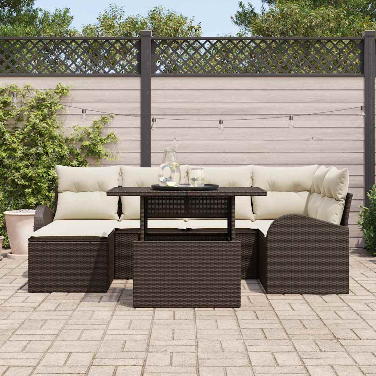 Outdoor-Sitzbereich mit braunem Korbsessel und Tisch, cremefarbenen Kissen und Holzzaun im Hintergrund.