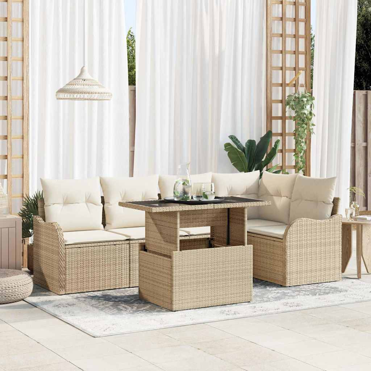 Outdoor-Sitzbereich mit Korbmöbeln, beigen Kissen, einem ansteigenden Tisch mit Glasplatte. Weiße Vorhänge und Pflanzen im Hintergrund.