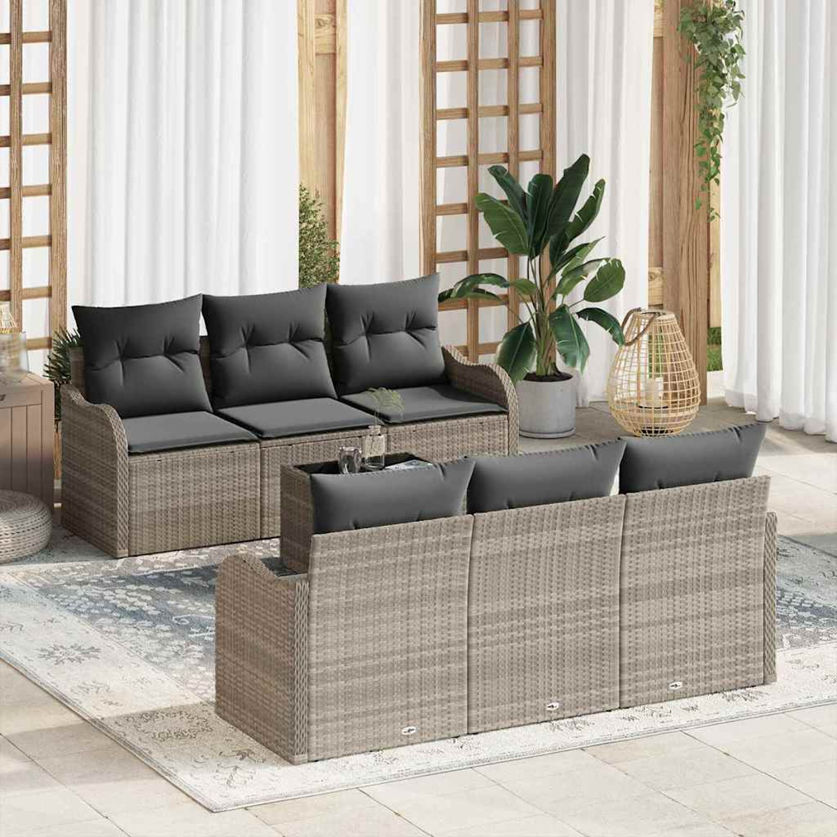 Geflochtenes Terrassenmöbel-Set mit grauen Kissen. Enthält zwei Sofas, einen Couchtisch und einen Teppich auf einer Terrasse.