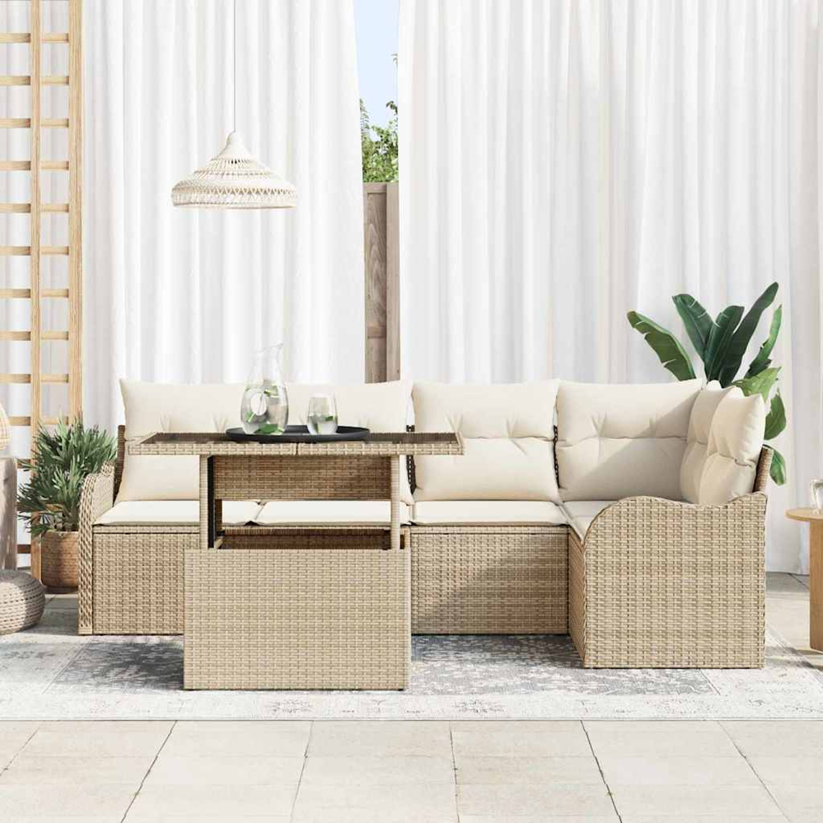 Rattan-Sofa im Freien mit cremefarbenen Kissen und einem Tisch. Weiße Vorhänge und eine Hängeleuchte sind im Hintergrund. Pflanzen sind ebenfalls sichtbar.