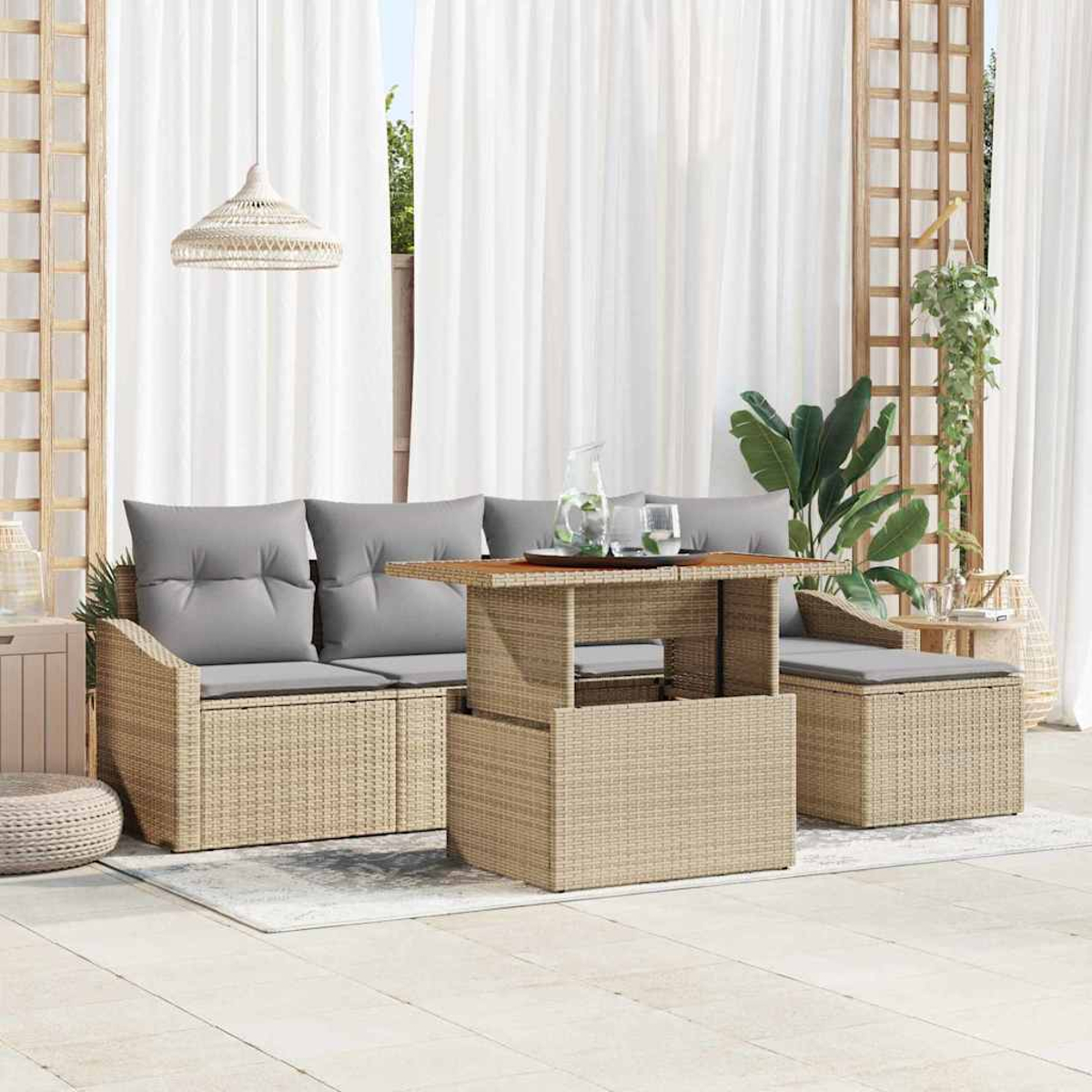 Gartenmöbel-Set aus Korbgeflecht mit grauen Kissen. Enthält Sofa, Tisch und Ottoman. Weiße Vorhänge und Pflanzen im Hintergrund.