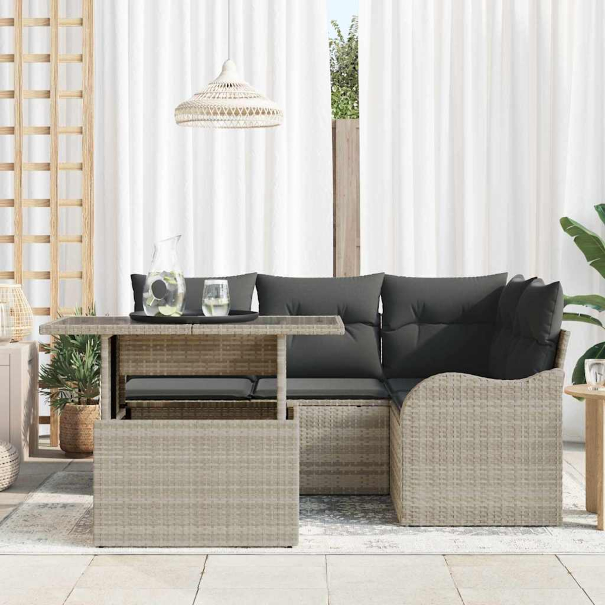 Gartenmöbel mit Tisch, Kissen und Wasserkrug. Weiße Vorhänge und eine Hängelampe im Hintergrund.