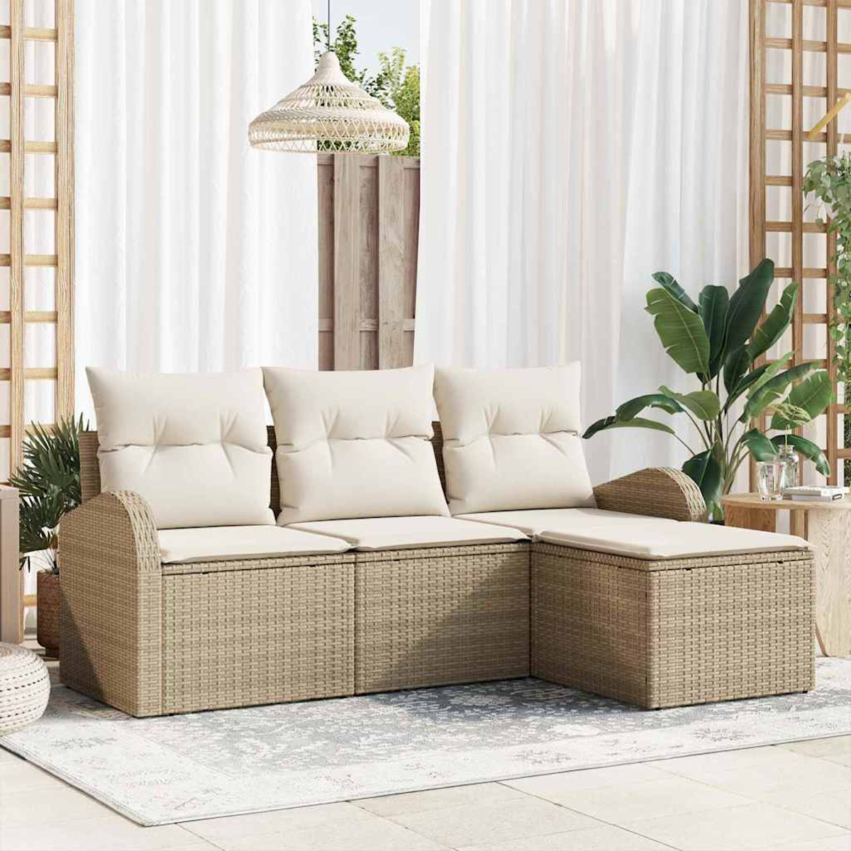 Una zona de estar al aire libre con un sofá de mimbre beige y cojines crema. Una alfombra y cortinas blancas completan la escena. Se ven plantas y una lámpara colgante.