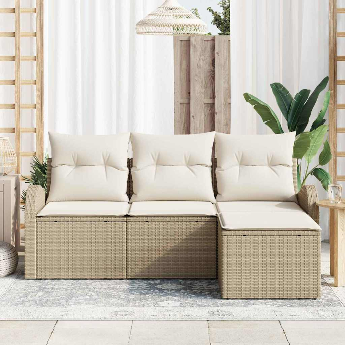 Sofá seccional exterior de mimbre beige con cojines crema sobre una alfombra estampada. El fondo muestra una cortina blanca.