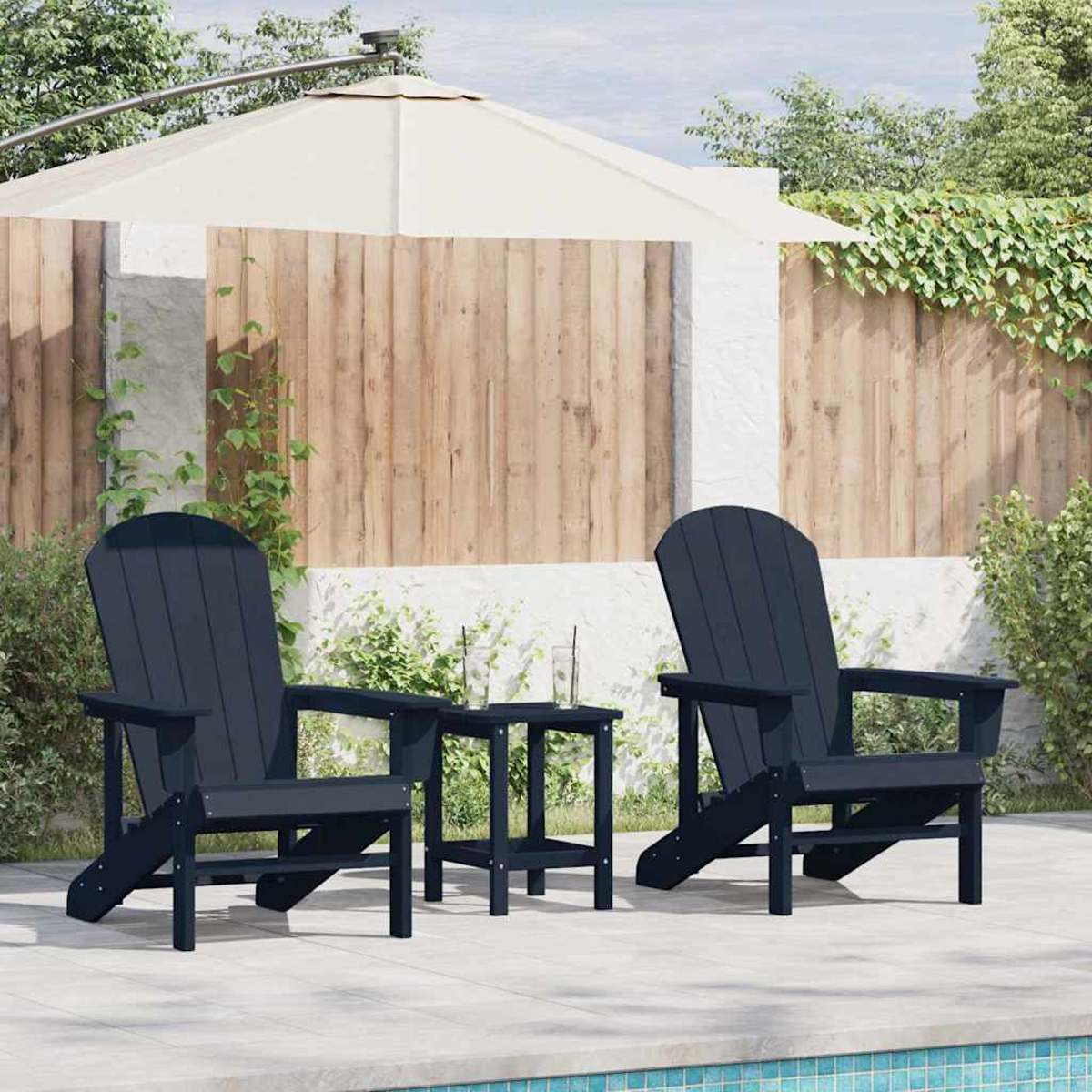 Dos sillas Adirondack azul marino y una mesa pequeña en un patio. Una sombrilla crema da sombra. Valla de madera y vegetación en el fondo.