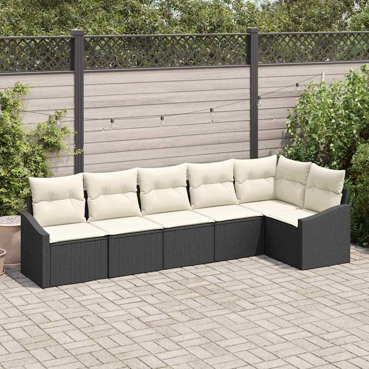 Modernes Outdoor-Ecksofa mit cremefarbenen Kissen auf einer Backstein-Terrasse. Ein Holzzaun und Grün bilden den Hintergrund.