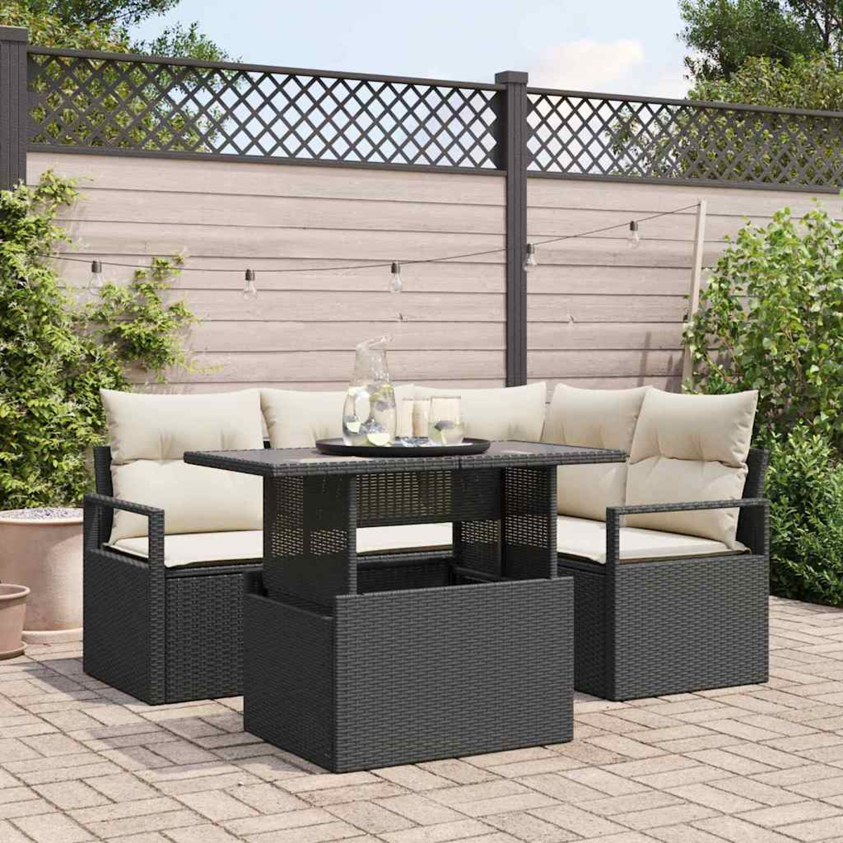 Garten-Terrassenset mit Tisch und zwei Stühlen. Im Hintergrund ein Zaun mit Lichterketten. Auf dem Tisch stehen eine Kanne und Gläser.