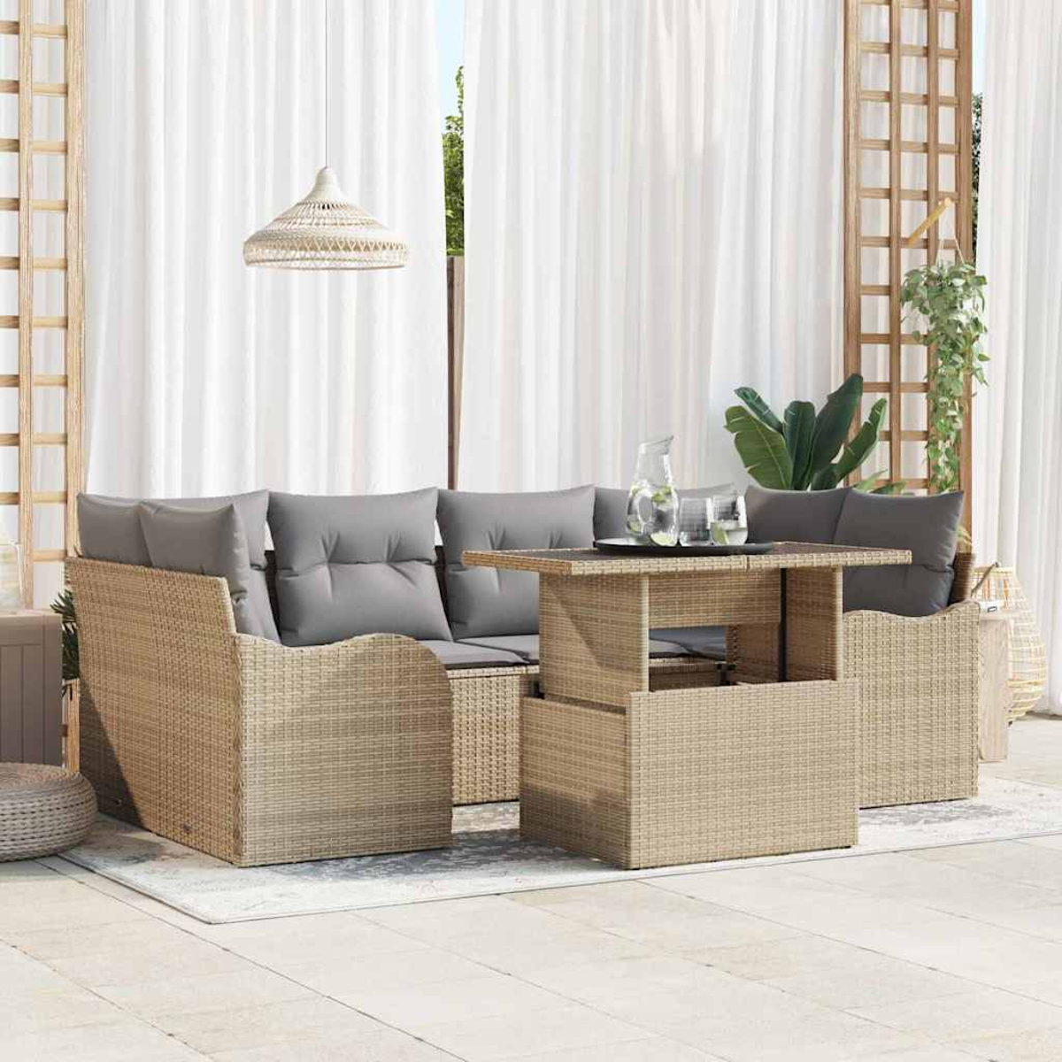 Juego de muebles de patio al aire libre con sofá de mimbre, mesa y cojines grises. Una jarra y vasos están sobre la mesa, con cortinas en el fondo.