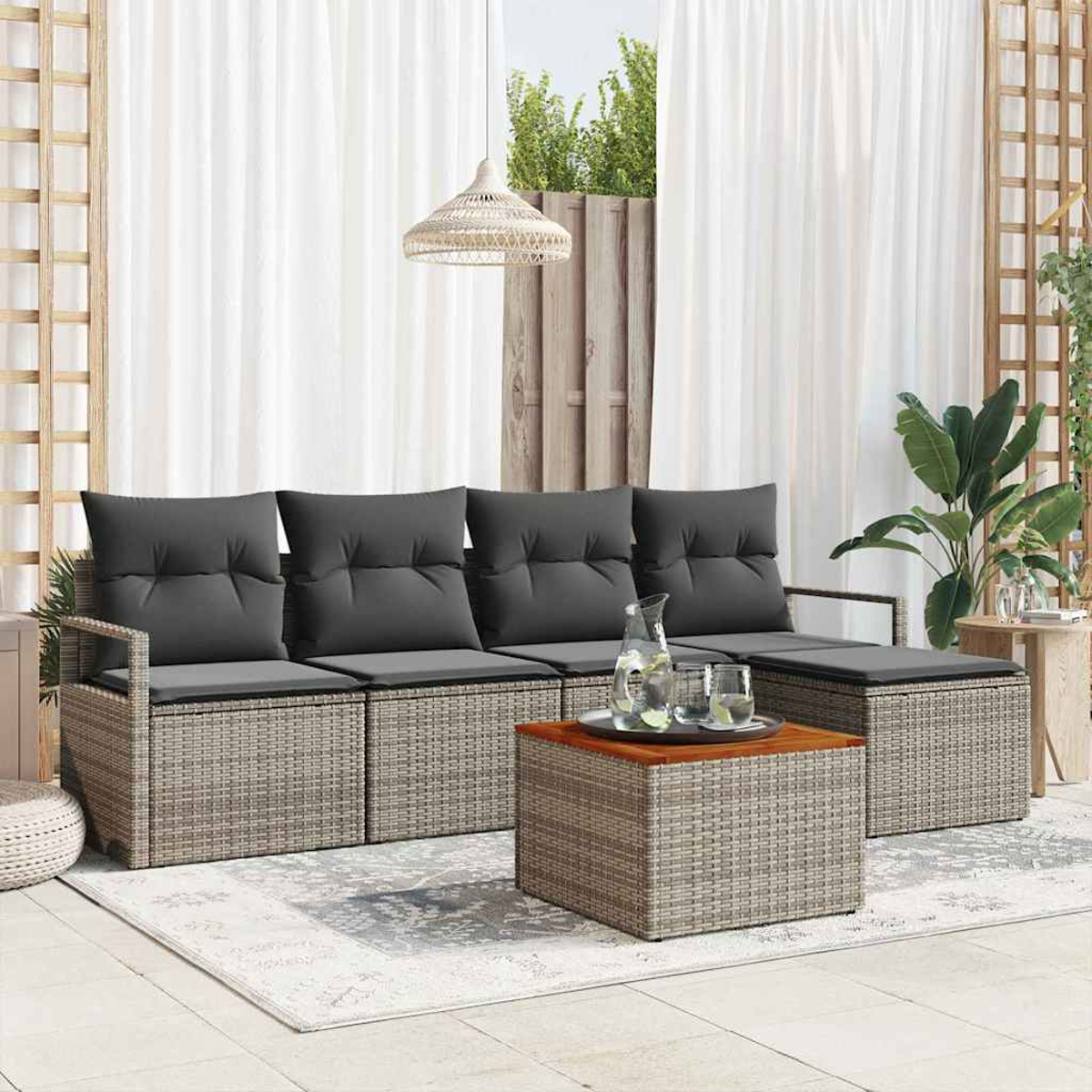 Garten-Set mit grauen Kissen und Korbgewebe. Mit Couchtisch, Getränken, weißen Vorhängen und einem Teppich.
