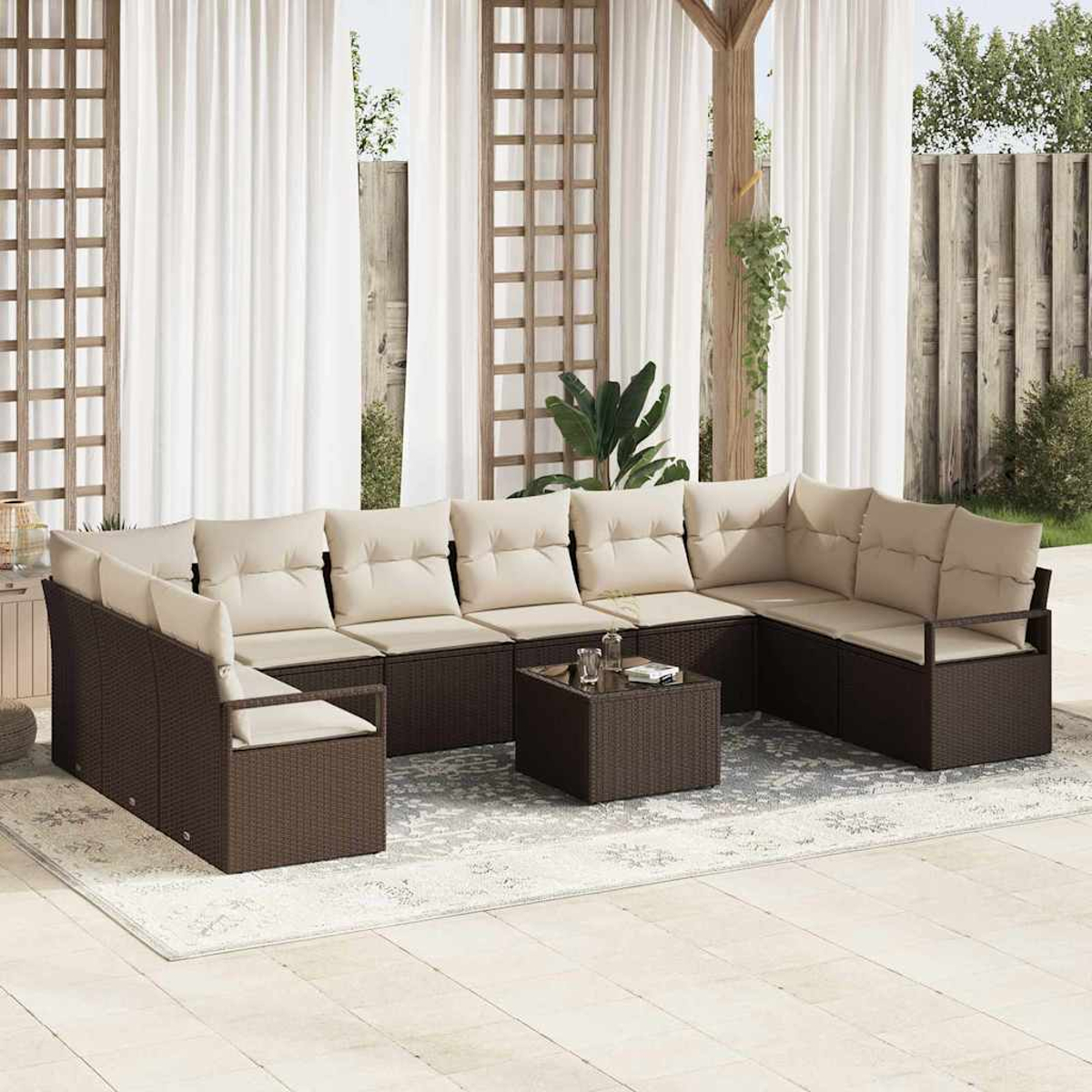 Außenbereich mit braunem Korbsessel und passendem Couchtisch. Beige Kissen und weiße Vorhänge im Hintergrund.