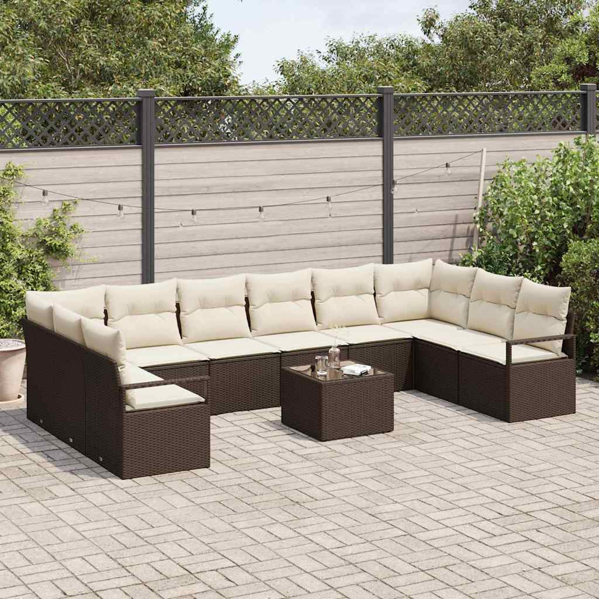 Ein braunes Korbsessel-Sofa mit cremefarbenen Kissen und einem quadratischen Couchtisch steht auf einer gepflasterten Terrasse. Ein Zaun und Blätterwerk sind im Hintergrund.