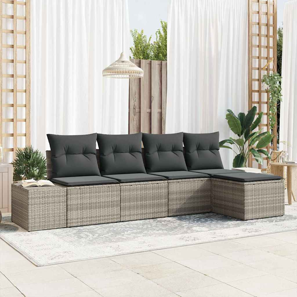 Outdoor-Korbsessel mit grauen Kissen. Weiße Vorhänge, eine Hängelampe und Pflanzen schaffen eine entspannte Terrasse.
