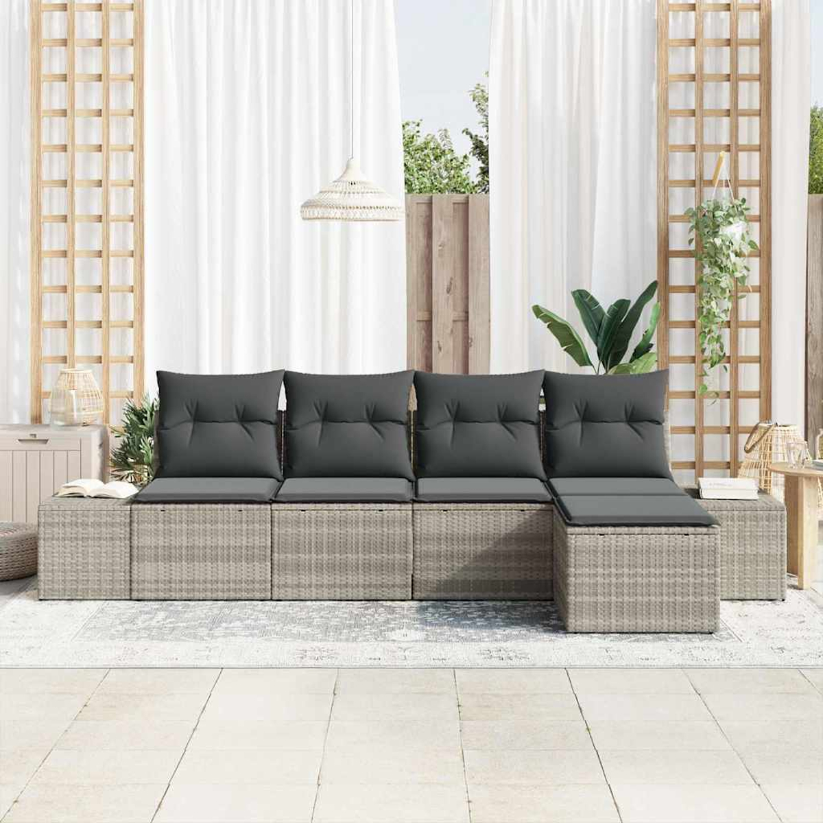 Outdoor-Wicker-Sofa mit grauen Kissen. Weiße Vorhänge, Holzgitter und Hängepflanze im Hintergrund. Hellfarbiger Boden.