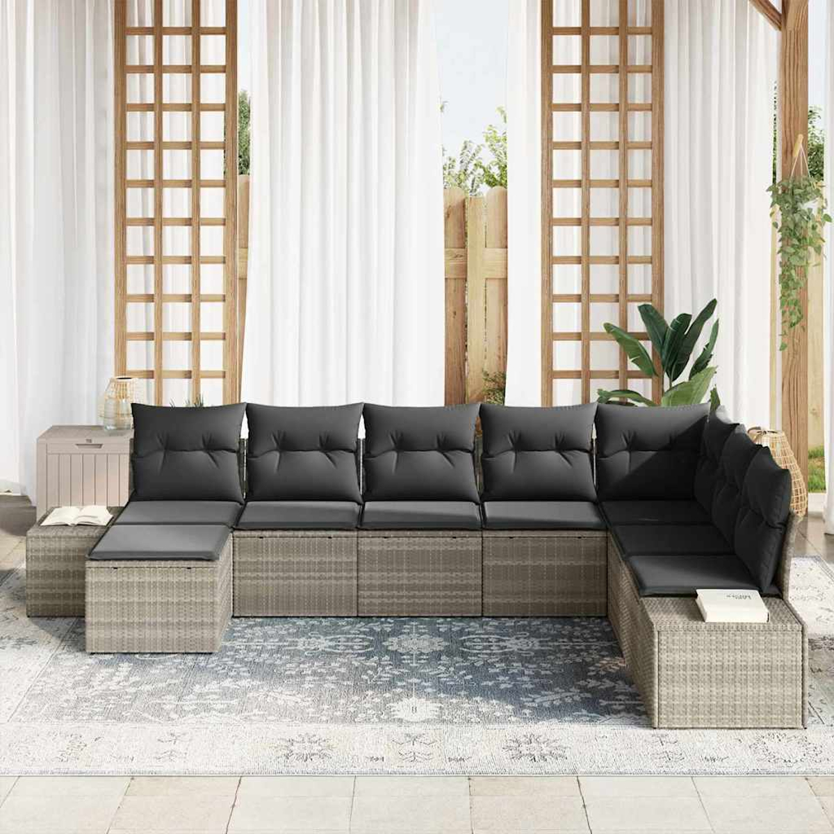 Un sofá seccional gris con cojines negros sobre una alfombra. Detrás, cortinas blancas, enrejado de madera y un armario.