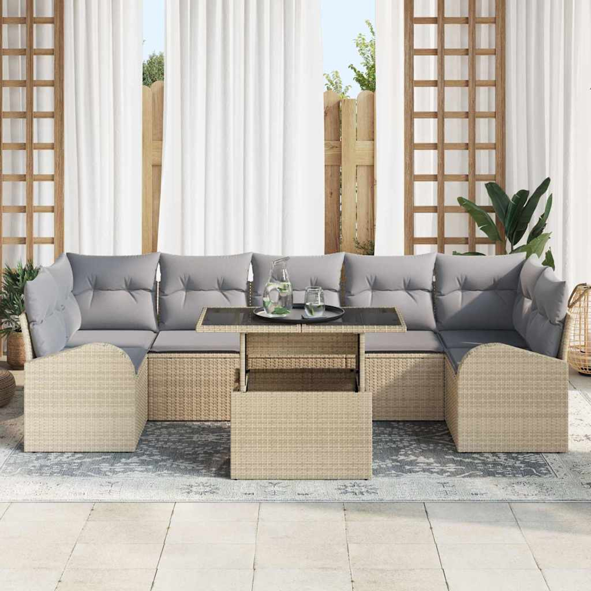 Outdoor-Ecksofa mit grauen Kissen und Korbbasis. Davor stehen ein Tisch mit Glasplatte und eine Wasserkaraffe.