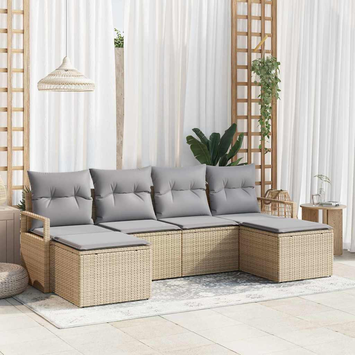 Juego de asientos para exteriores con cojines grises. Base de mimbre. Cortinas blancas al fondo. Enrejado de madera decorativo con plantas.