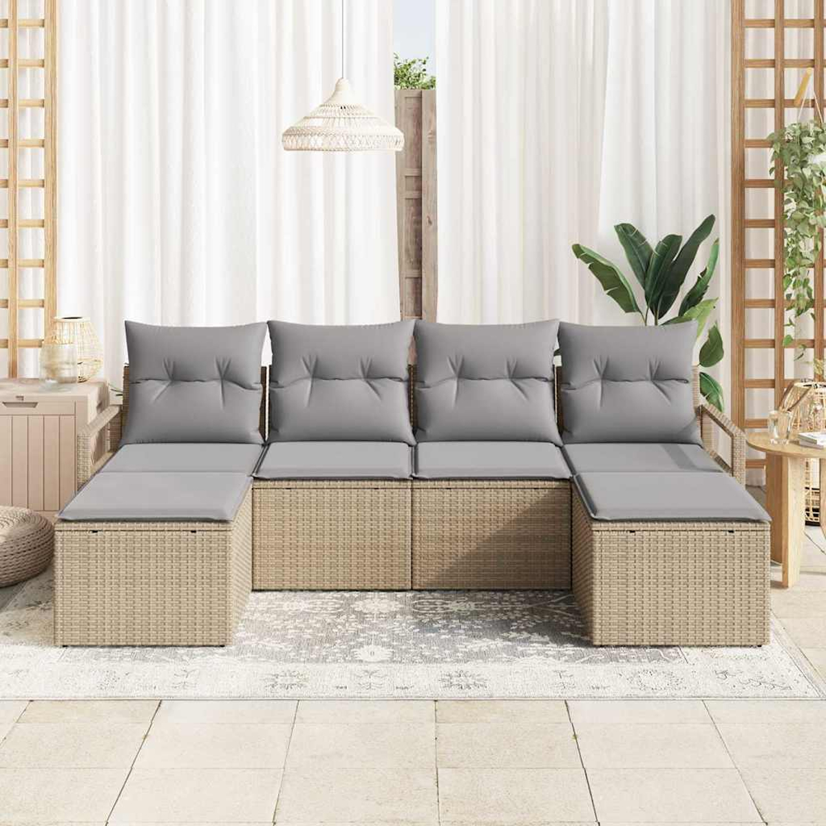 Sofá seccional para exteriores con cojines grises. Base de mimbre. Cortinas blancas al fondo. Plantas y una lámpara colgante también son visibles.
