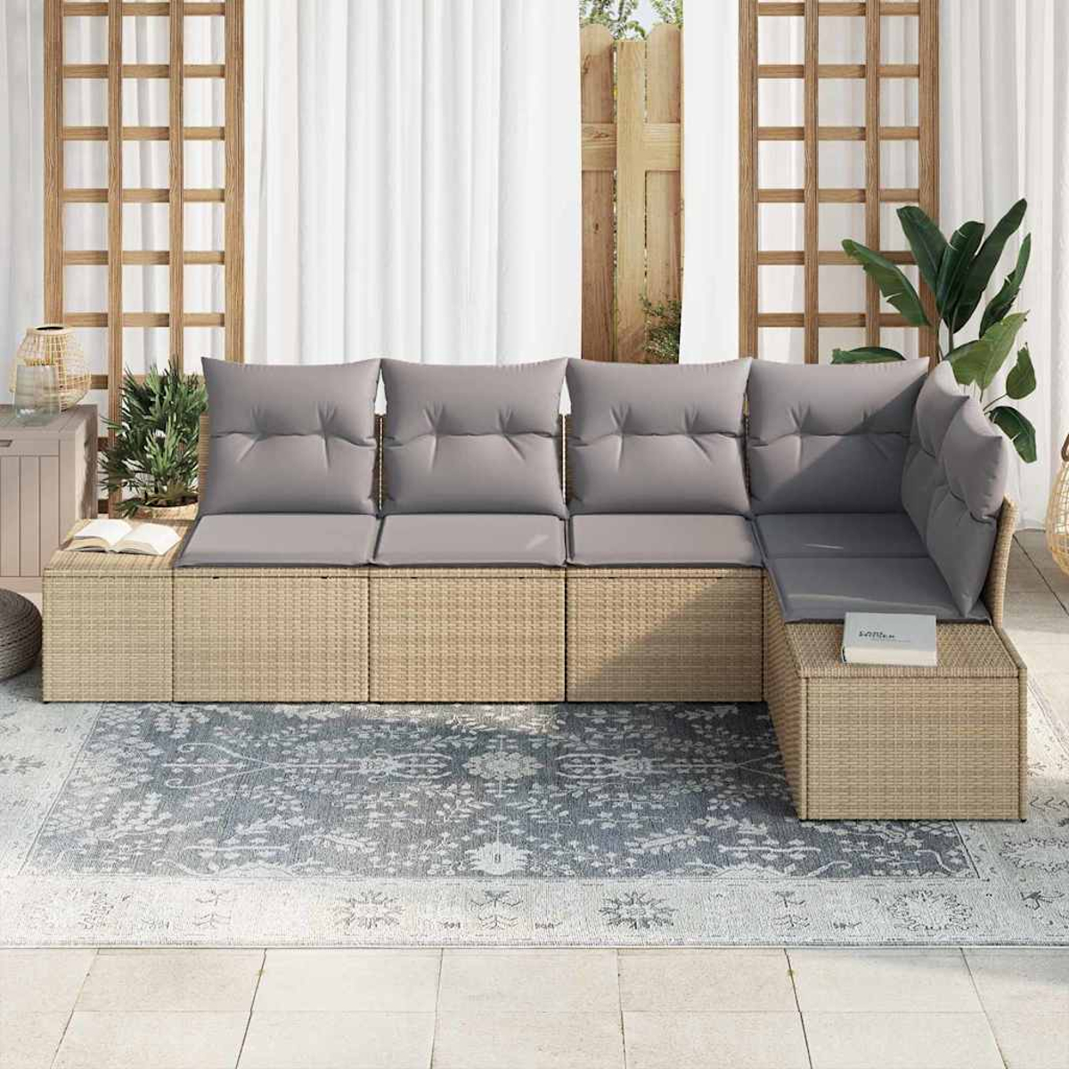 Geflochtenes Ecksofa mit grauen Kissen auf einem gemusterten Teppich. Ein Buch und Pflanzen befinden sich in der Nähe. Der Hintergrund umfasst weiße Vorhänge und ein Gitter.