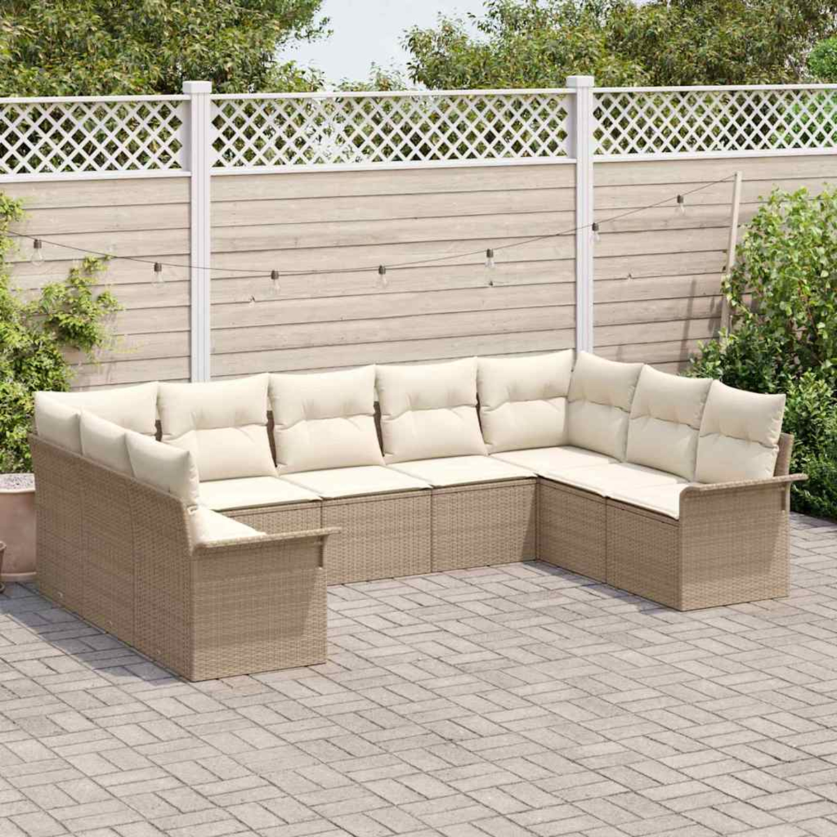 Ein Outdoor-Rattansofa mit cremefarbenen Kissen steht auf einer Ziegelterrasse. Im Hintergrund ein weißer Zaun und Grün.