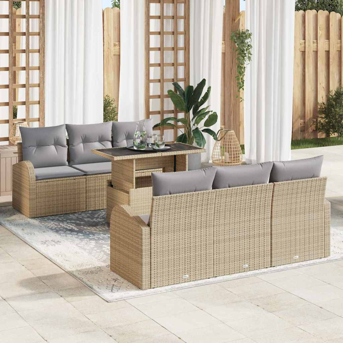 Terrassenmöbel-Set mit Rattansofas, Couchtisch und grauen Kissen. Vorhänge, Pflanzen und Holzzaun im Hintergrund.