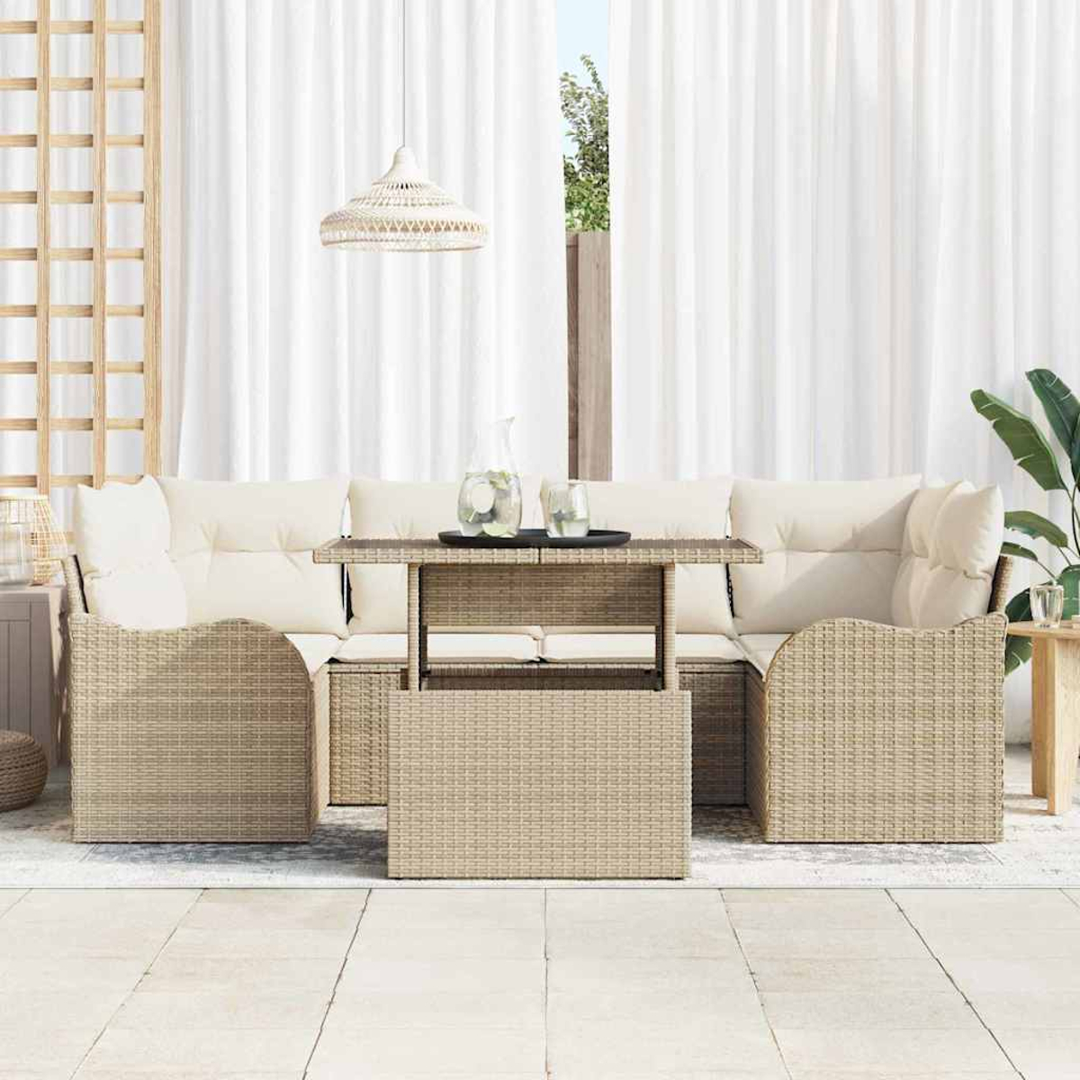 Garten-Korbmöbel-Set mit cremefarbenen Kissen. Tisch mit Getränken. Weiße Vorhänge und eine Hängelampe im Hintergrund.