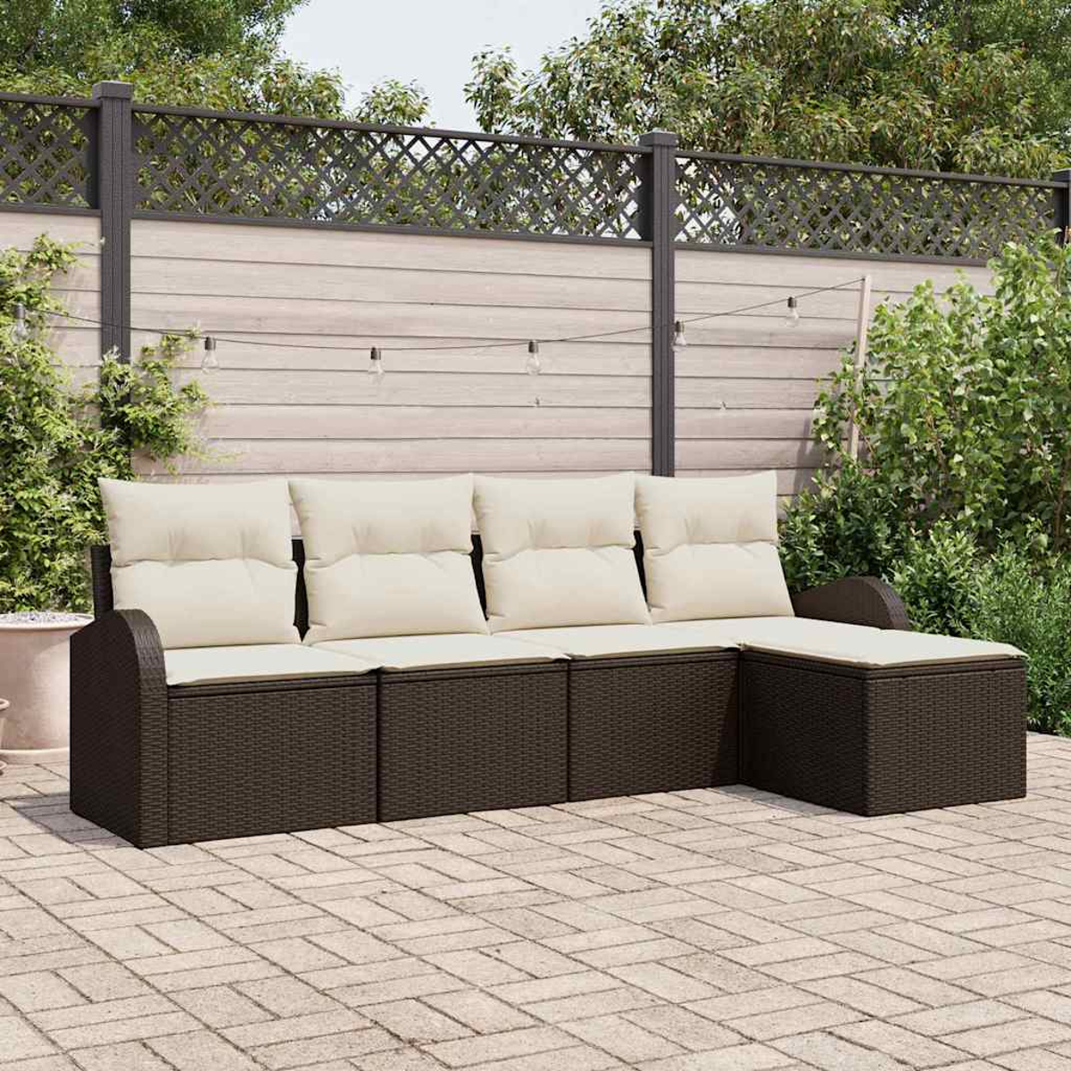 Ein Ecksofa im Freien mit cremefarbenen Kissen auf einer Backsteinterrasse. Im Hintergrund ein Holzzaun und Grün.