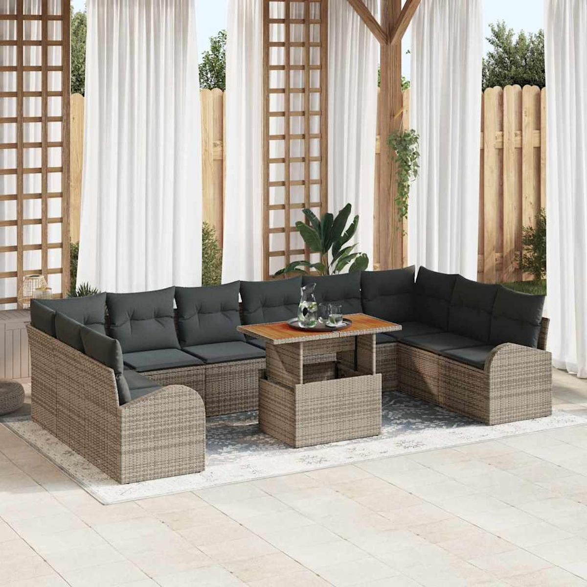 Terrassenset mit grauen Kissen. Tisch mit Gläsern und Krug. Weiße Vorhänge im Hintergrund, Holzkonstruktion.