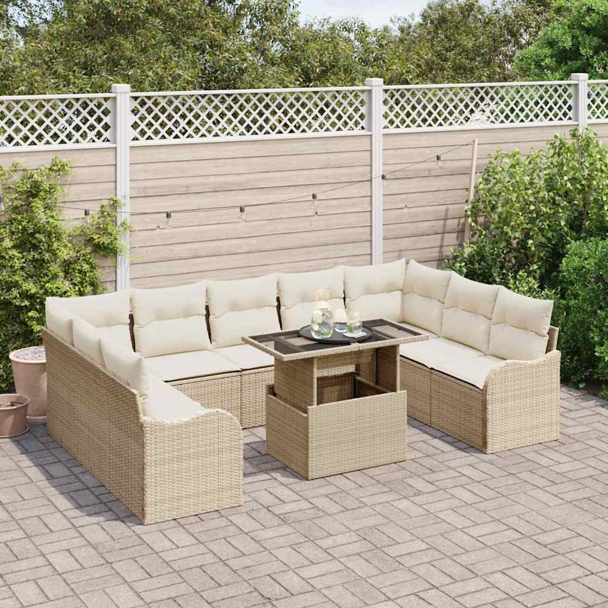 Terrassengarnitur mit beigen Kissen, einem Tisch mit Getränken, auf einer Ziegelterrasse mit weißem Zaun im Hintergrund.