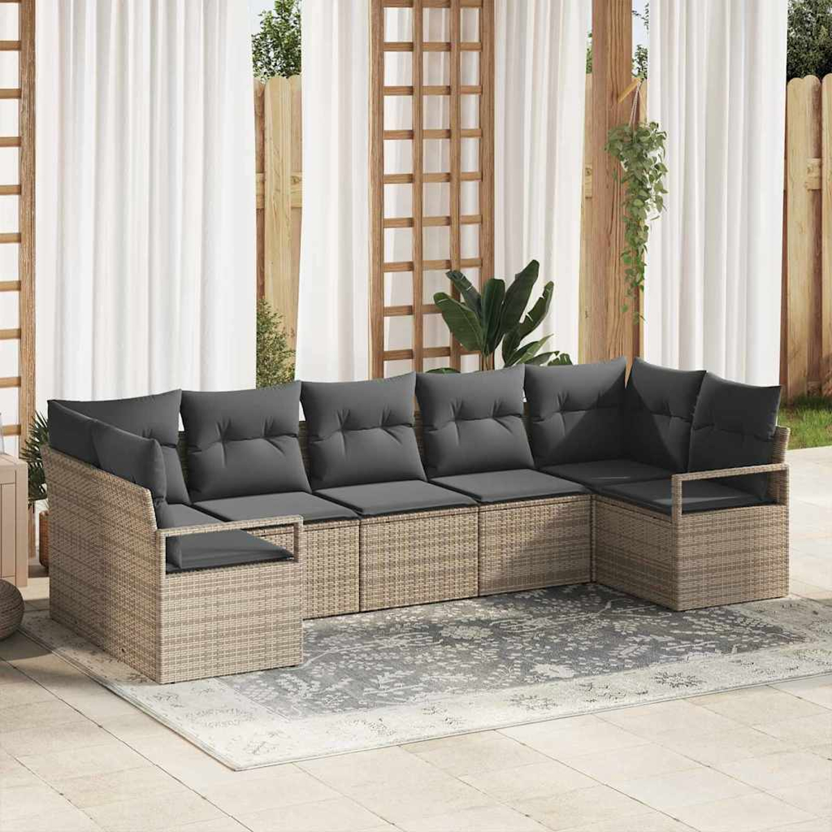 Ein Ecksofa im Freien mit grauen Kissen steht auf einem gemusterten Teppich. Weiße Vorhänge und Holzstrukturen bilden den Hintergrund.