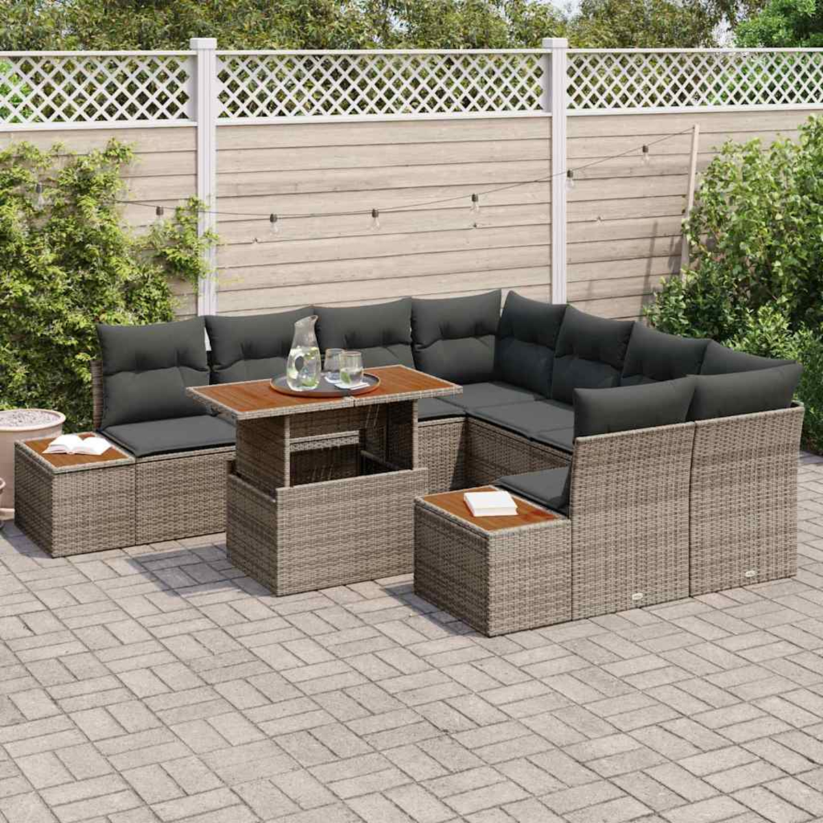 Gartenmöbel-Set mit grauen Kissen, einem Holztisch und einem weißen Zaun im Hintergrund, auf einer Backstein-Terrasse.