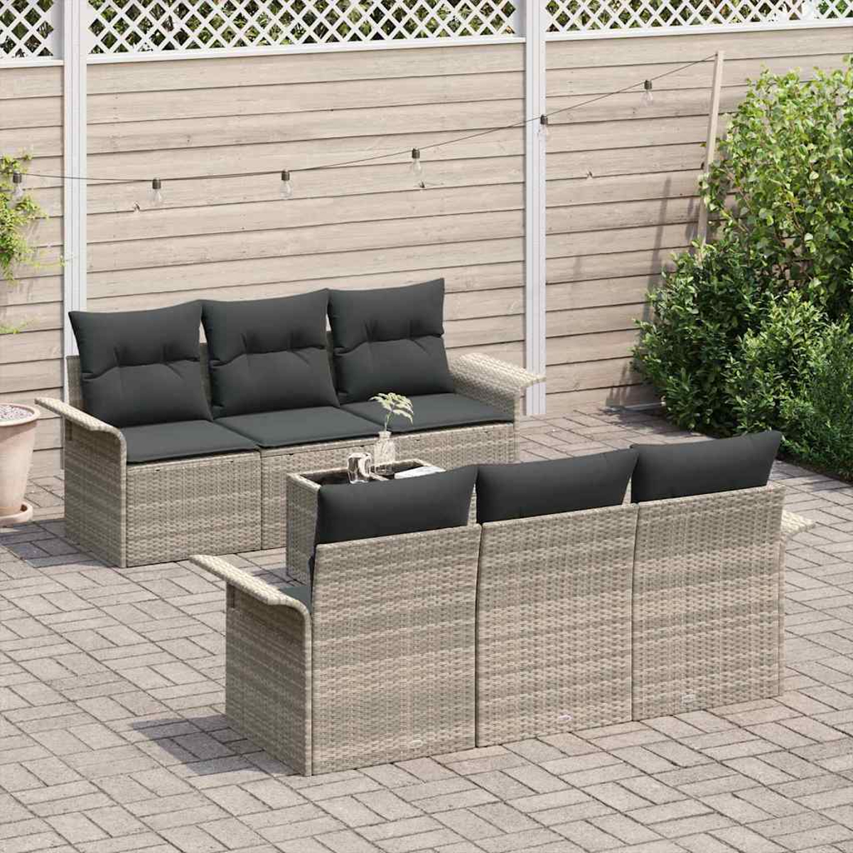 Gartenmöbel-Set mit grauen Kissen. Enthält ein Sofa, zwei Stühle und einen Tisch. Der Hintergrund zeigt einen Holzzaun.