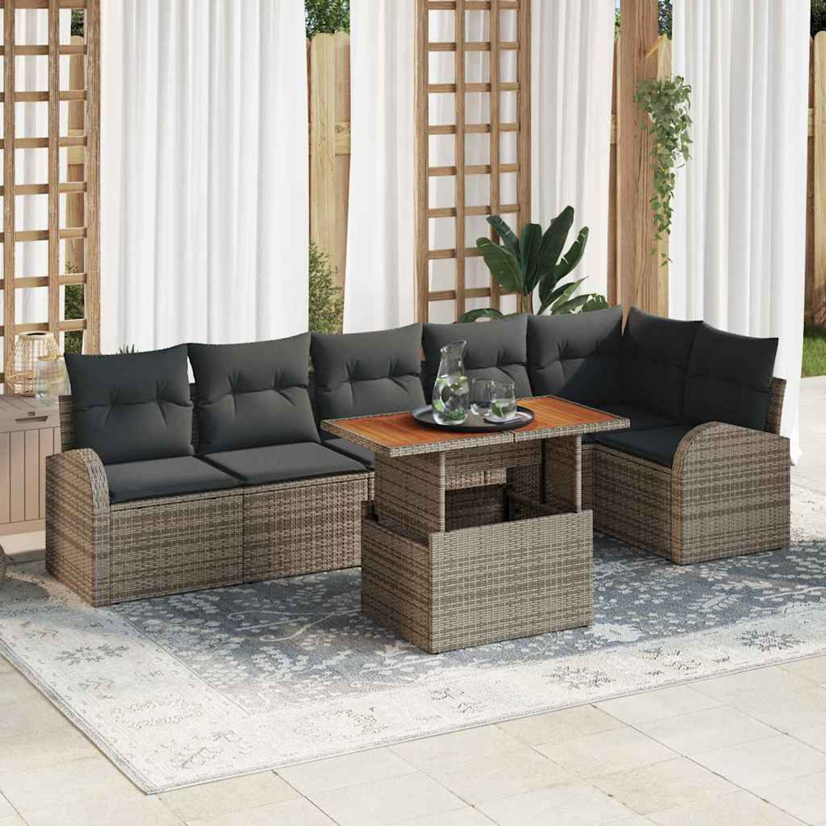 Terrassengarnitur mit grauen Kissen, einem Holztisch und einem gemusterten Teppich. Weiße Vorhänge und ein Holzgitter im Hintergrund.