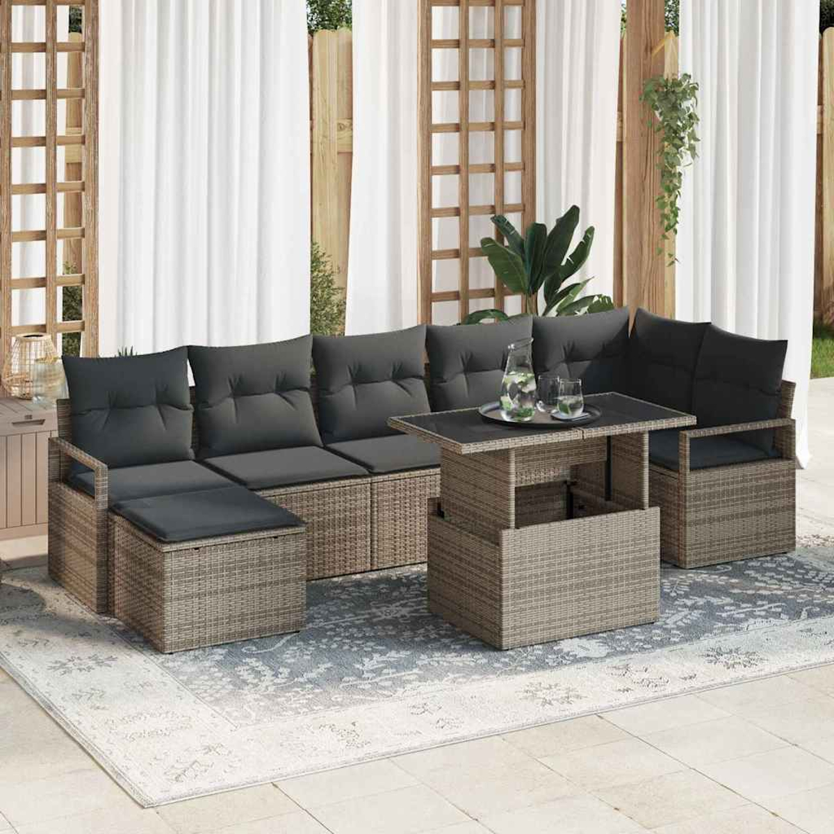 Garten-Sitzgruppe mit grauen Kissen, Tisch und Teppich. Weiße Vorhänge und Holzgitter im Hintergrund.