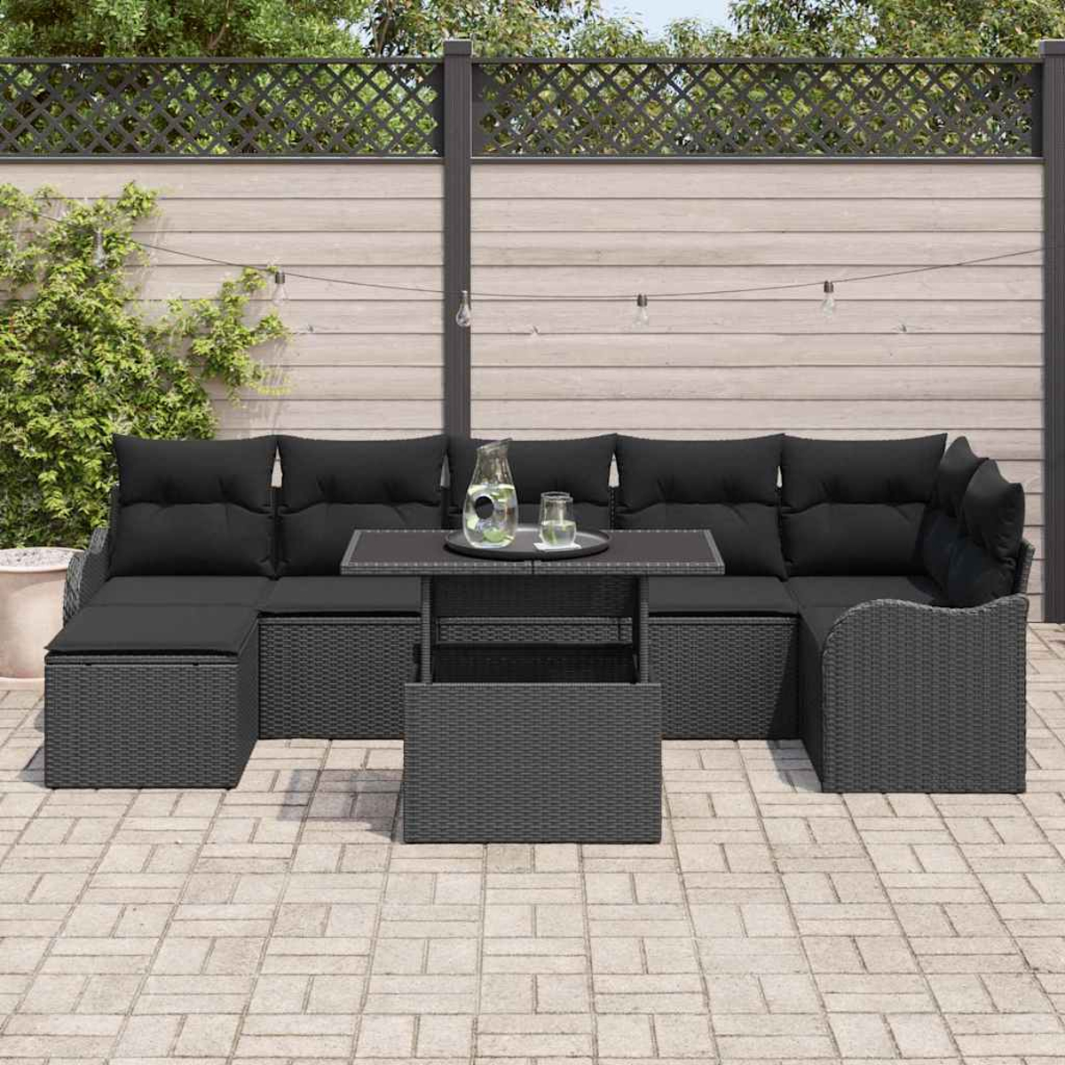 Schwarzes Outdoor-Korbmöbelset mit Kissen und einem Tisch auf einer Ziegelterrasse. Im Hintergrund ein Zaun.