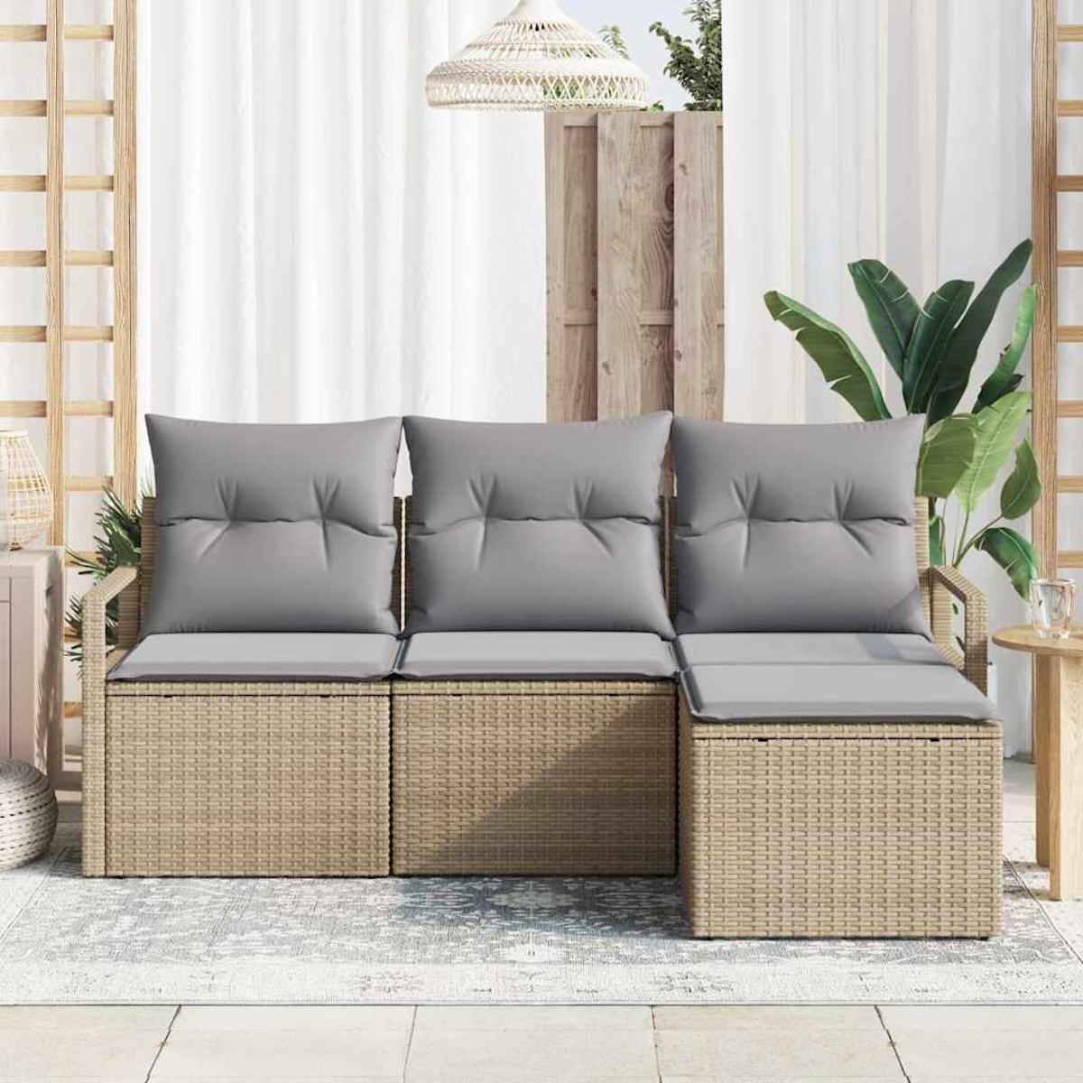 Geflochtenes Outdoor-Sofa mit grauen Kissen. Holzakzente und ein Teppich befinden sich im Vordergrund. Hintergrund hat einen Holzzaun und Pflanzen.
