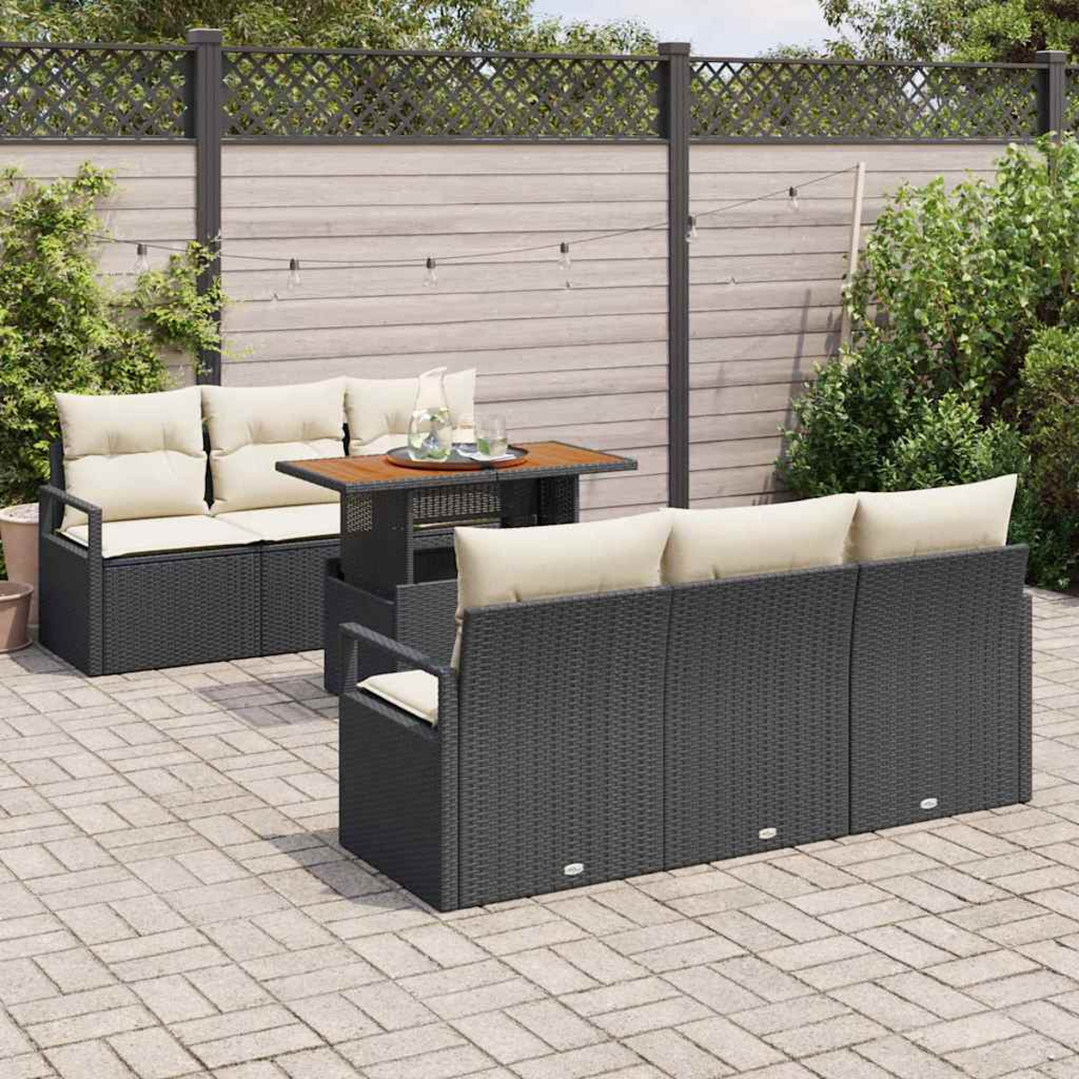 Terrassenmöbel-Set mit dunkelgrauem Korbsessel, Sofa und Tisch auf einer Stein-Terrasse. Beige Kissen und eine Holzplatte.